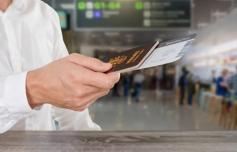Passager tenant un passeport et une carte d'embarquement avant un vol.
