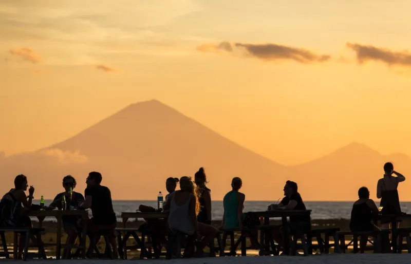 Voyageurs admirant le coucher du soleil à Gili Trawangan avec le volcan Agung en arrière-plan