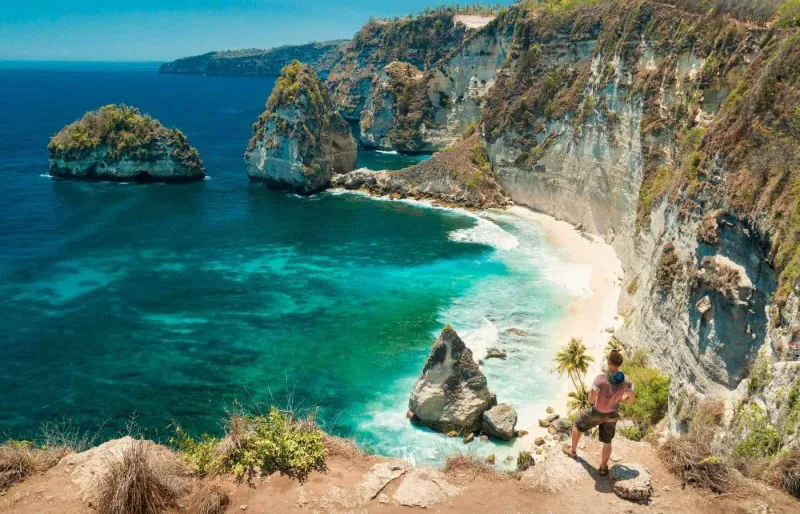 Voyageur admirant Diamond Beach à Nusa Penida depuis les falaises dominant cette crique aux eaux turquoise
