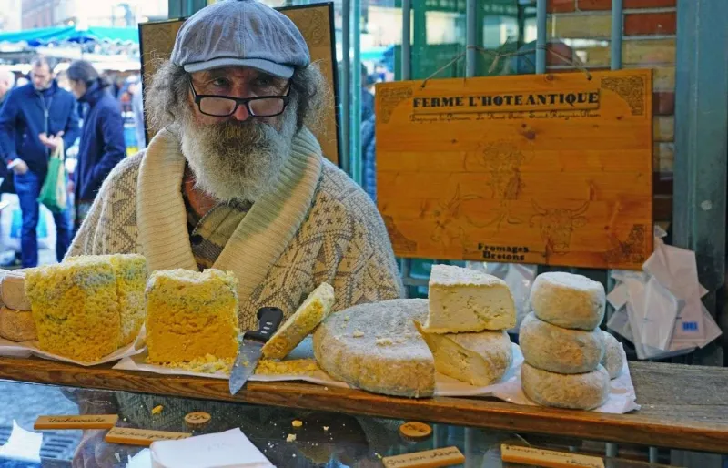 Un chaland devant des fromages fermiers au marché des Lices à Rennes