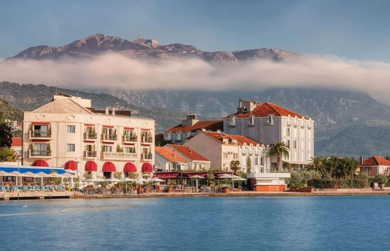 Hôtels et restaurants en bord de mer à Tivat au Monténégro avec le mont Lovćen en arrière-plan
