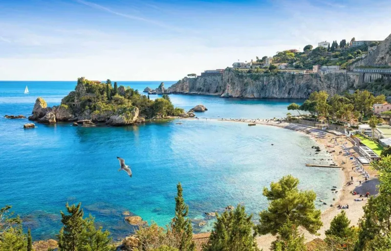 Vue sur Isola Bella à Taormine avec son banc de sable reliant l’île au rivage et les eaux turquoise de la mer Ionienne