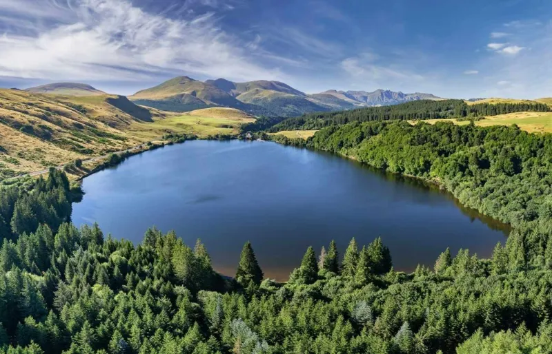 Vue panoramique du lac de Guéry entouré de forêts avec le massif du Sancy en arrière-plan dans le Puy-de-Dôme.