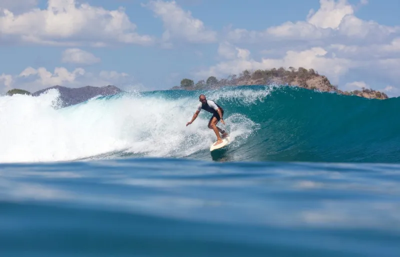 Surfeur sur une vague à Pantai Jelenga, l’un des meilleurs spots de surf de Sumbawa en Indonésie