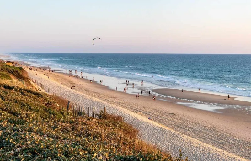 Vue de la plage du Vivier à Biscarrosse depuis les dunes, avec un kitesurfeur au-dessus de l'océan Atlantique