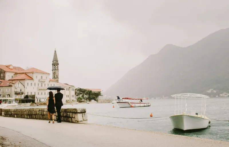Couple sous un parapluie sur le front de mer des bouches de Kotor au Monténégro par temps de pluie