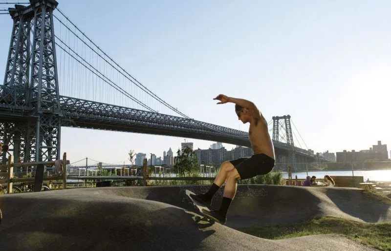 Skateur au Brooklyn Bike Park avec le pont de Williamsburg en arrière-plan