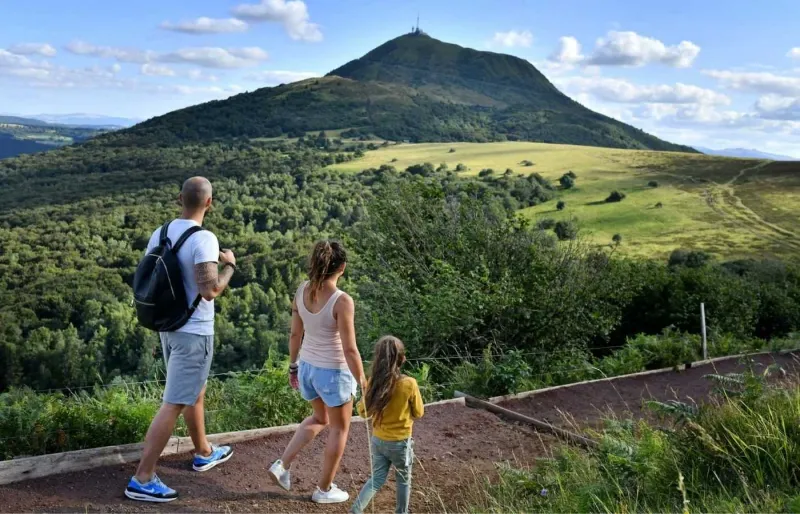 Famille en randonnée face au puy de Dôme dans la chaîne des Puys, au cœur des volcans d'Auvergne.
