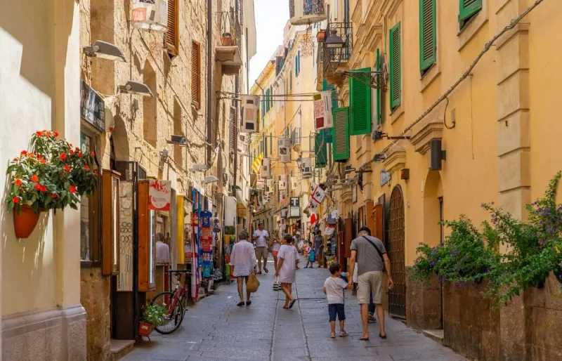 Des touristes se promènent dans les ruelles pavées du centre historique d'Alghero, l'une des plus belles villes médiévales de Sardaigne.