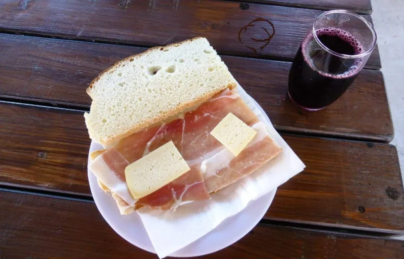 Assiette de Njeguški pršut et de fromage de Njeguši accompagnée d'un verre de vin rouge au Monténégro