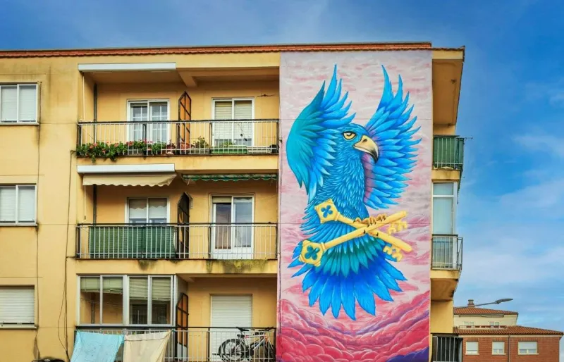 Fresque de street art représentant un perroquet bleu géant sur un immeuble du Barrio del Oeste à Salamanque en Espagne