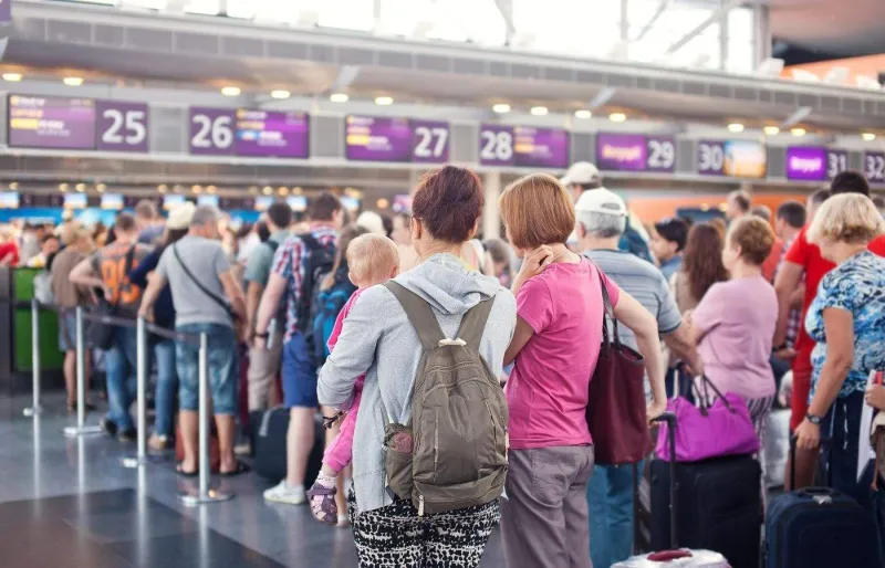 Passagers faisant la queue à l'aéroport avant un embarquement pouvant être concerné par un surbooking.
