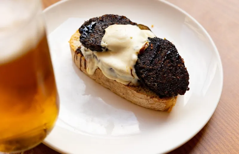 Tapa espagnole garnie de morcilla, d'aubergine et d'aïoli servie avec une bière à Salamanque