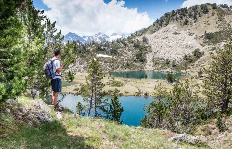 Randonneur face aux lacs d'altitude du massif du Néouvielle dans les Hautes-Pyrénées