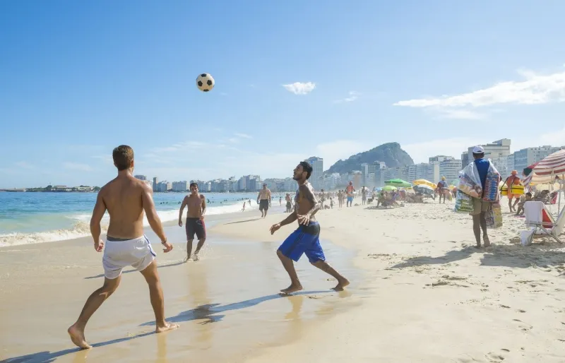 Personnes jouant au football sur la plage de Copacabana à Rio de Janeiro, l'une des plages les plus mythiques du Brésil 