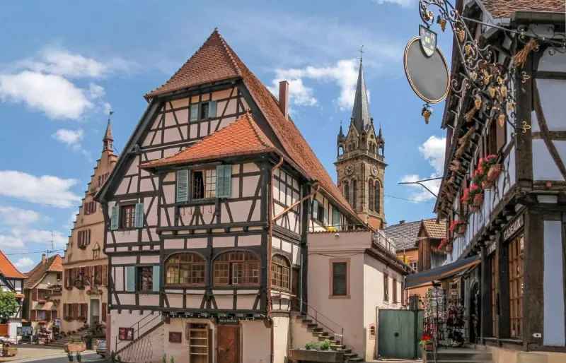 Maisons à colombages et clocher de l'église Saint-Étienne dans le centre historique de Dambach-la-Ville