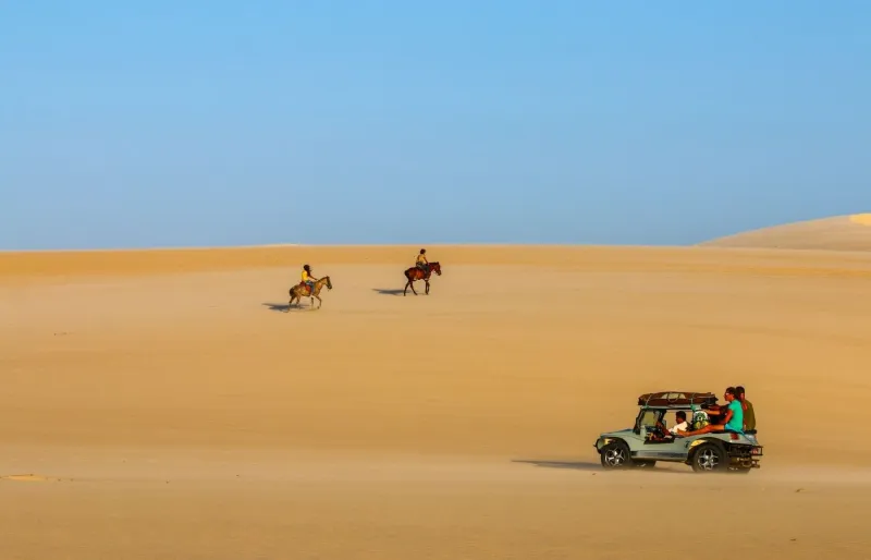 Buggy et cavaliers traversant les dunes de Jericoacoara dans le Ceará, l'un des plus beaux paysages du Brésil