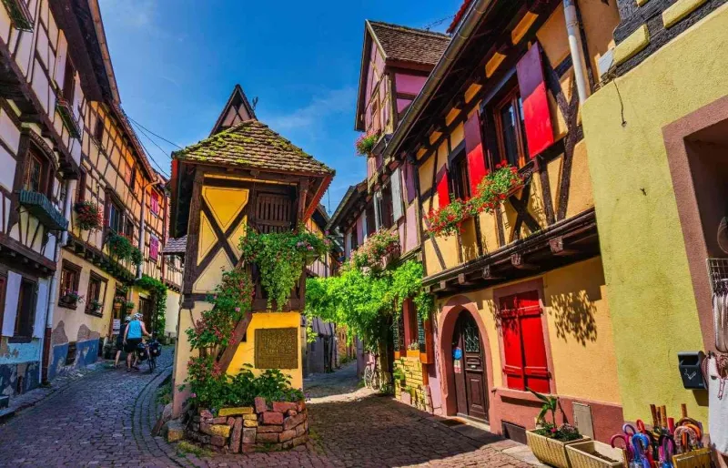 Rue pavée bordée de maisons à colombages colorées dans le village d'Eguisheim en Alsace