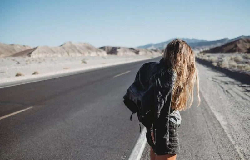 Voyageuse faisant de l'auto-stop seule au bord d'une route aux Etats-Unis.