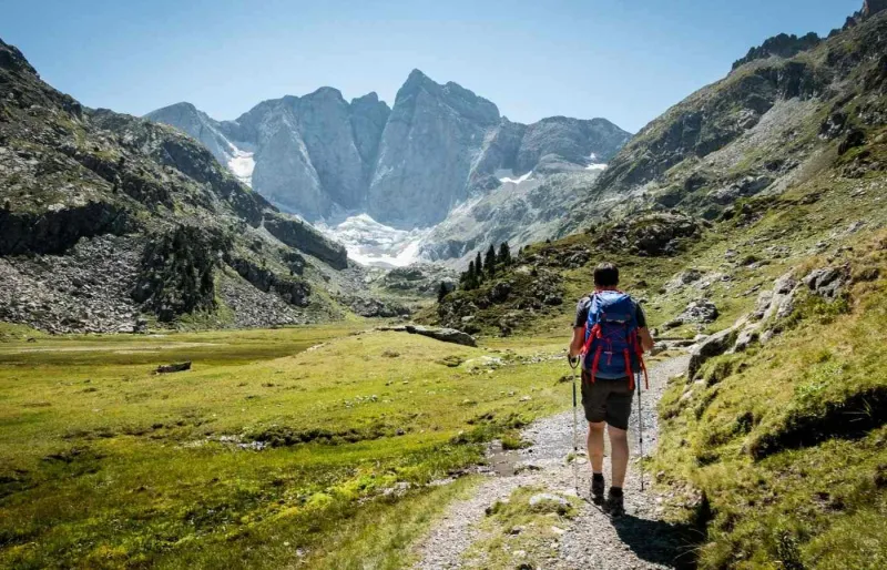 Randonneur sur le GR®10 face au massif du Vignemale dans les Pyrénées