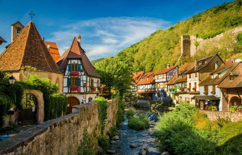 Maisons à colombages bordant la Weiss avec les ruines du château de Kaysersberg en Alsace