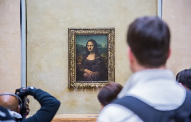 Des visiteurs photographient La Joconde de Léonard de Vinci au musée du Louvre à Paris.