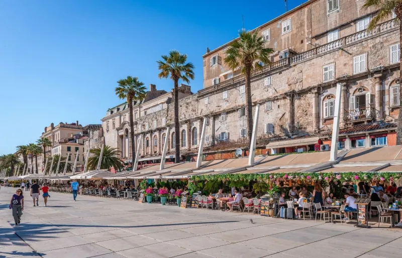 Promenade Riva à Split en Croatie avec ses palmiers, ses terrasses de cafés et son front de mer sous un ciel ensoleillé