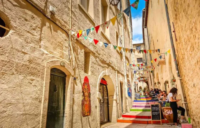 Ruelle du quartier de l'Écusson dans le centre historique de Montpellier avec ses façades anciennes et son escalier coloré.