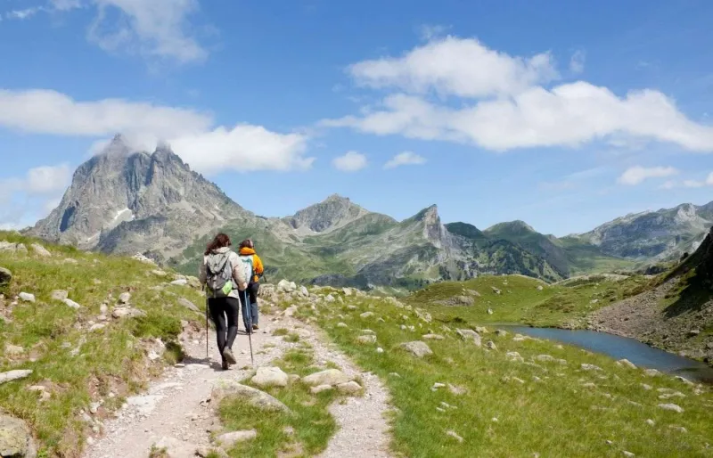 Randonneurs sur le sentier des lacs d'Ayous face au Pic du Midi d'Ossau dans les Pyrénées
