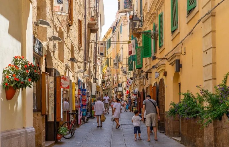 Ruelle du quartier médiéval d'Alghero bordée de boutiques et de bâtiments historiques en Sardaigne