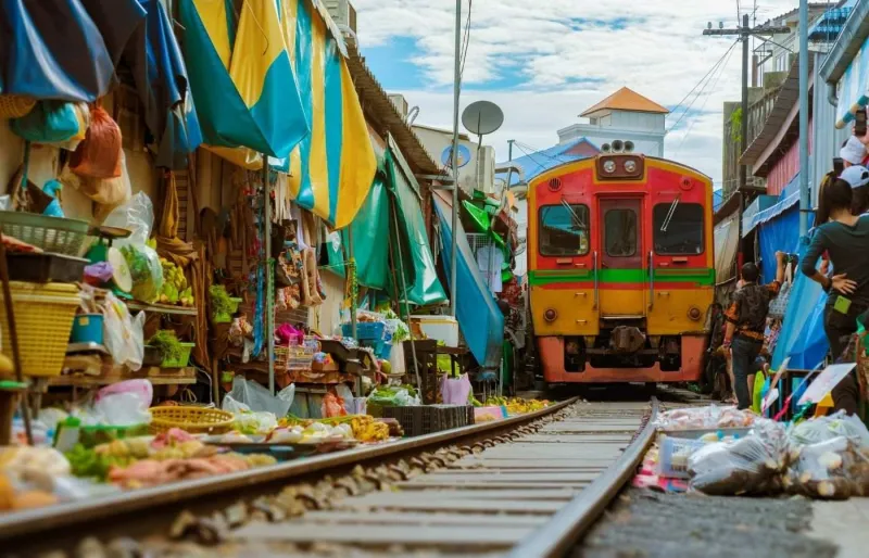Le train traverse le marché de Mae Klong, en Thaïlande, tandis que les commerçants replient leurs étals à son passage.