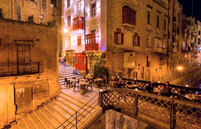 Restaurants et terrasses animés dans les rues de La Valette, à Malte, à la tombée de la nuit