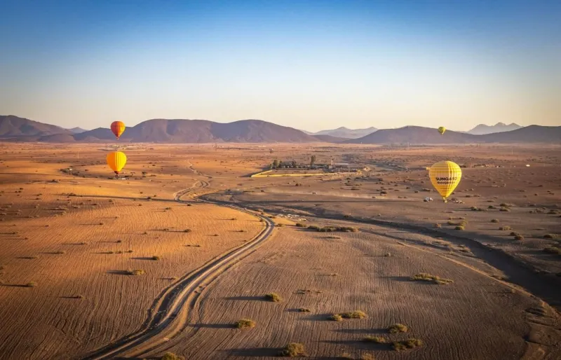 Montgolfières au-dessus du désert près de Marrakech avec les montagnes de l'Atlas en arrière-plan
