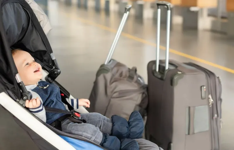 Bébé en poussette avec des valises pour partir en voyage