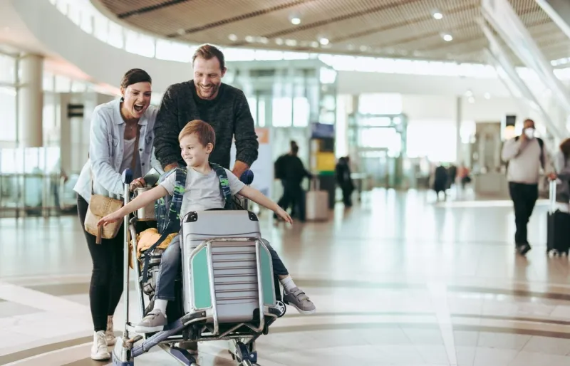 Famille avec un enfant et une valise à roulettes dans un aéroport