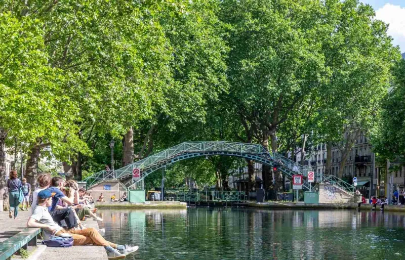 Passerelle au-dessus du canal Saint-Martin et promeneurs sur les quais à Paris