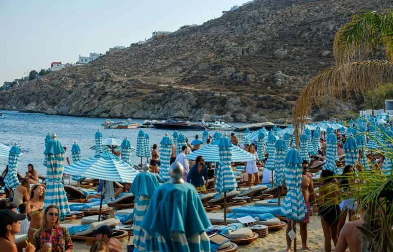 Transats et parasols sur le sable de Psarou, face aux bateaux au mouillage