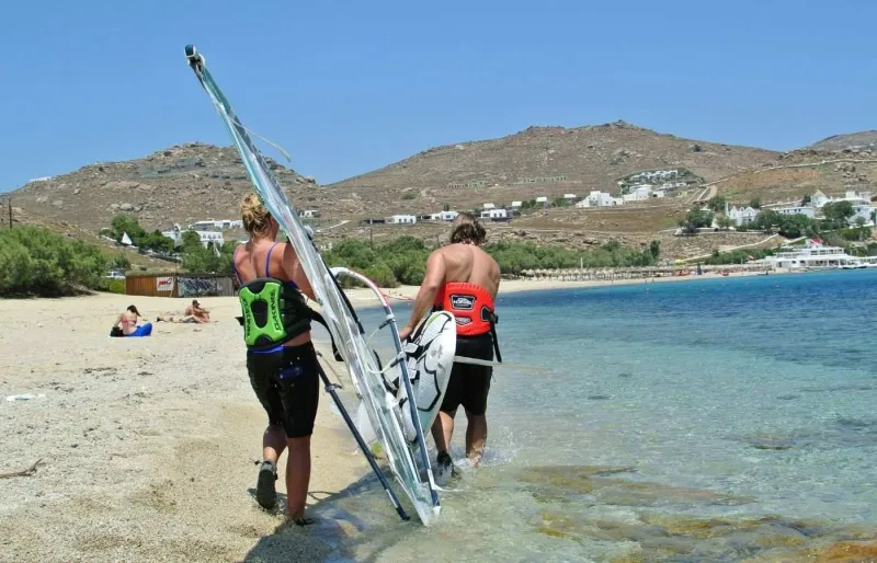 Planchistes rejoignant la mer avec leur planche à voile sur la plage de Kalafatis à Mykonos.