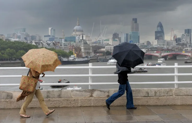 Promeneurs sous la pluie à Londres avec des parapluies face à la City