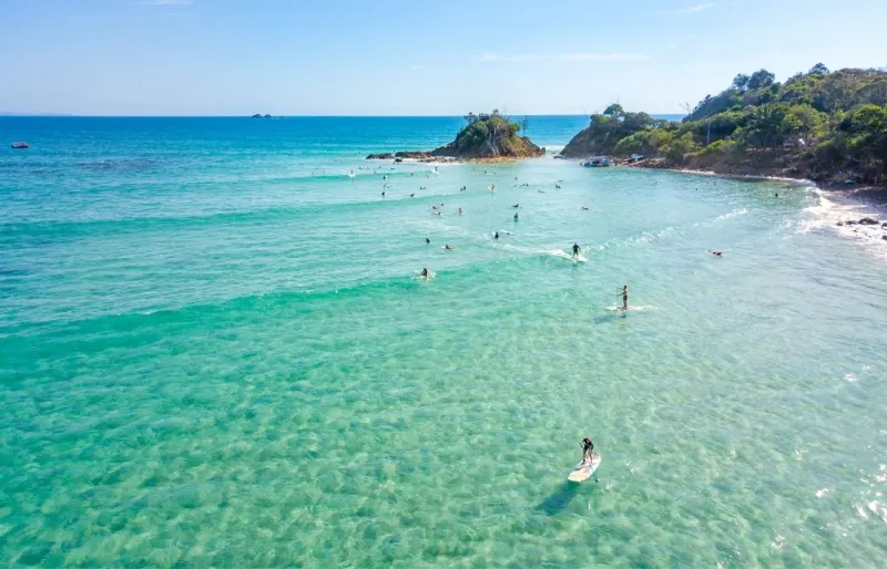 Surfeurs et paddleurs à The Pass, célèbre spot de surf de Byron Bay en Nouvelle-Galles du Sud, Australie