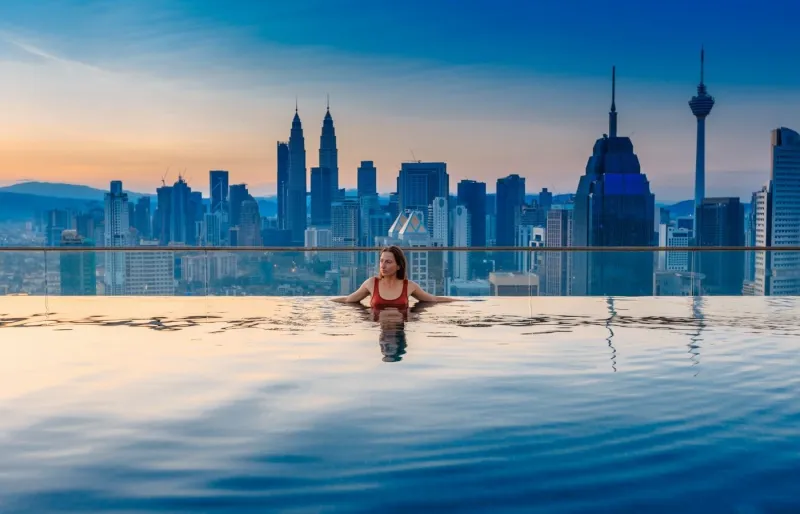 Femme dans une piscine avec vue sur les tours Petronas à Kuala Lumpur