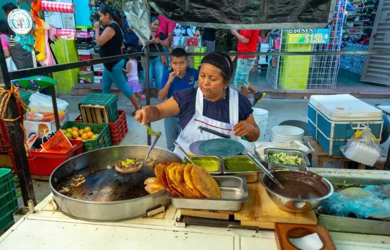 Stand de cuisine traditionnelle à Oaxaca préparant des tlayudas sur un marché