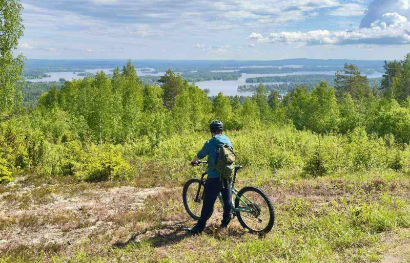 Cycliste en e-fatbike sur les hauteurs de Tahko avec vue sur le lac Syväri en Finlande