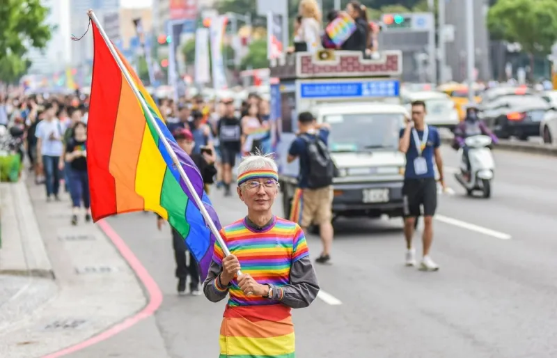 Participant à la Pride de Taipei portant un drapeau arc-en-ciel