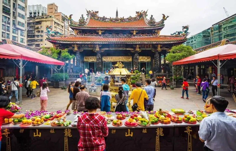Visiteurs au temple Longshan à Taipei devant des offrandes